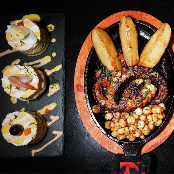 Peruvian dishes: causa with egg, shrimp, and olive, alongside grilled octopus with potatoes and corn.