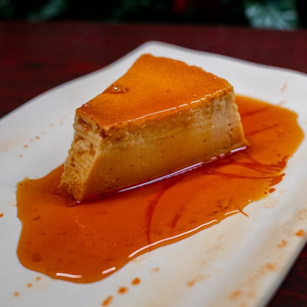 A slice of Peruvian flan with caramel sauce on a white plate at Cebiche-Bar.