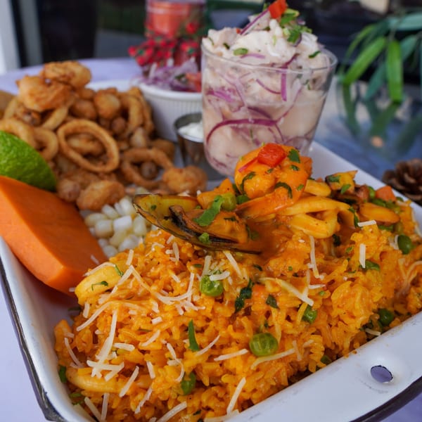 Peruvian seafood platter with arroz con mariscos, fried calamari, ceviche, and sweet potato.
