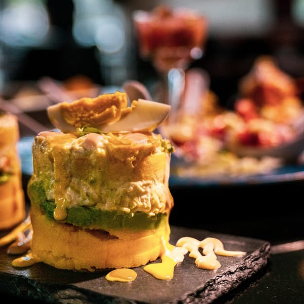 Peruvian causa, a layered potato dish with avocado, chicken, and a hard-boiled egg on top.